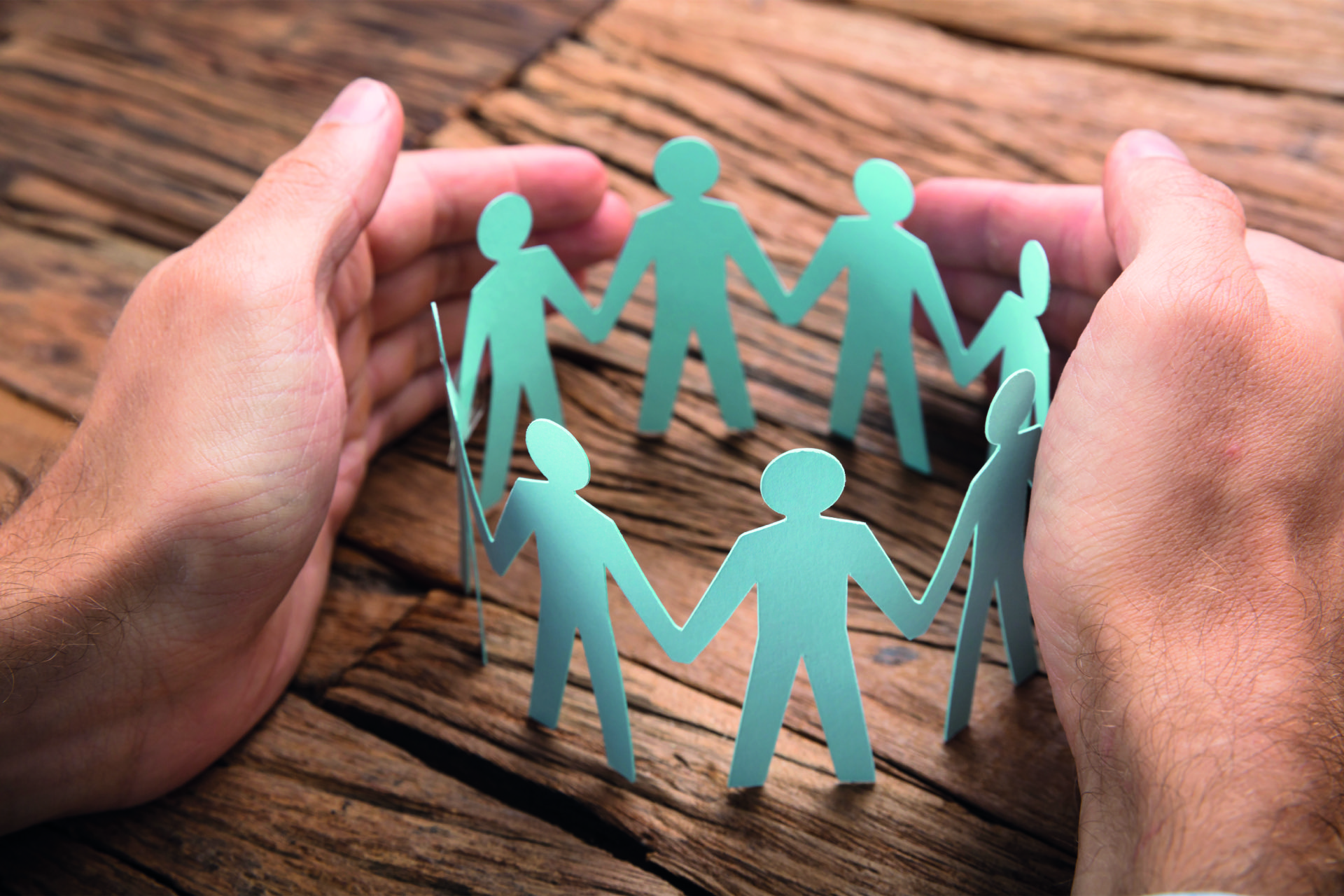 Ein Kreis aus Papierpersonensilhouette umringt von zwei Händen.